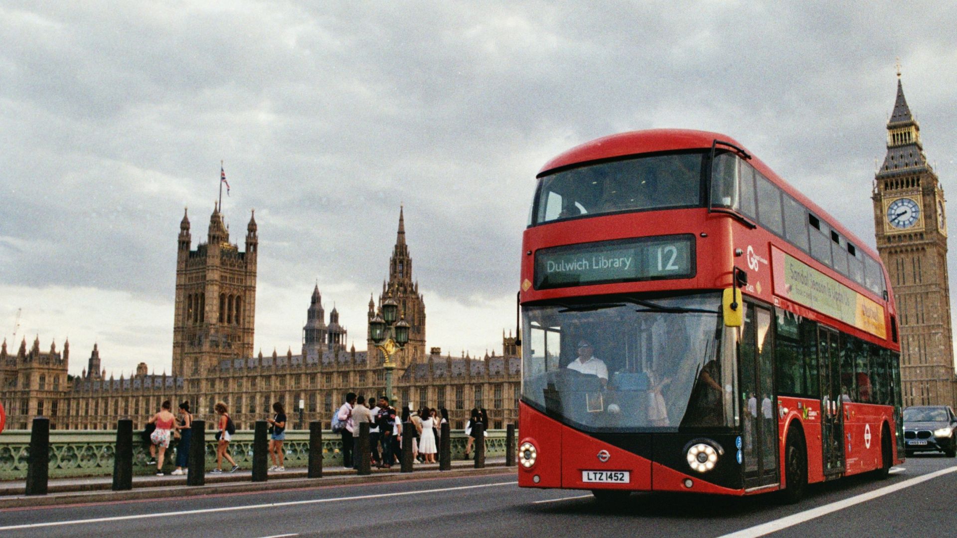 A double-decker bus passes the houses of parliament.