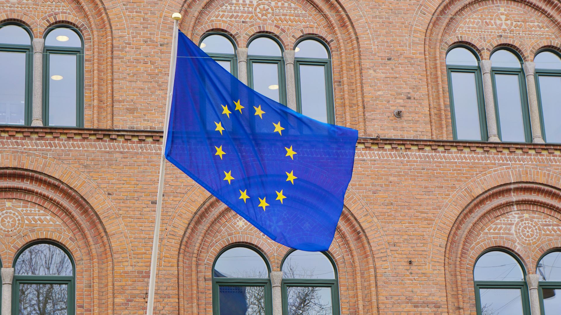 a european flag flying in front of a brick building