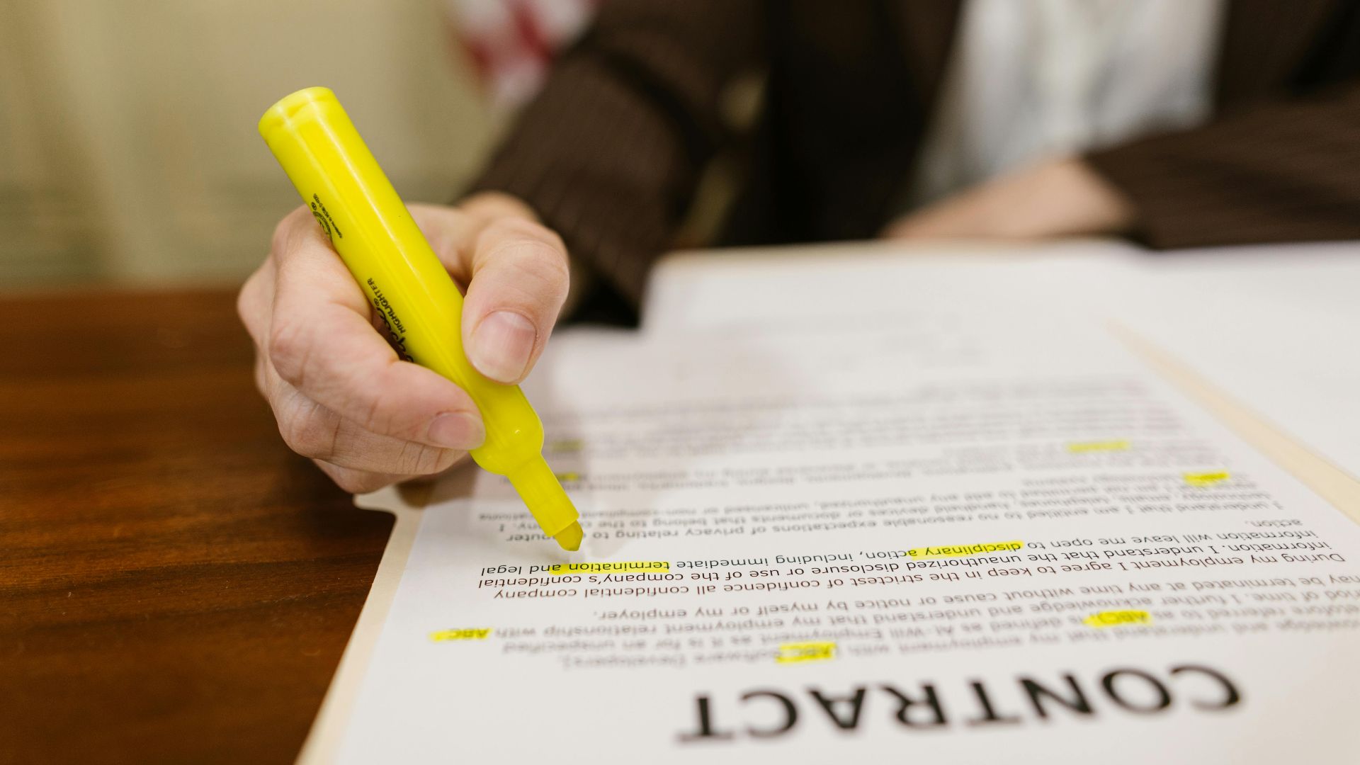 A close-up of a hand highlighting a contract, emphasizing important legal terms.