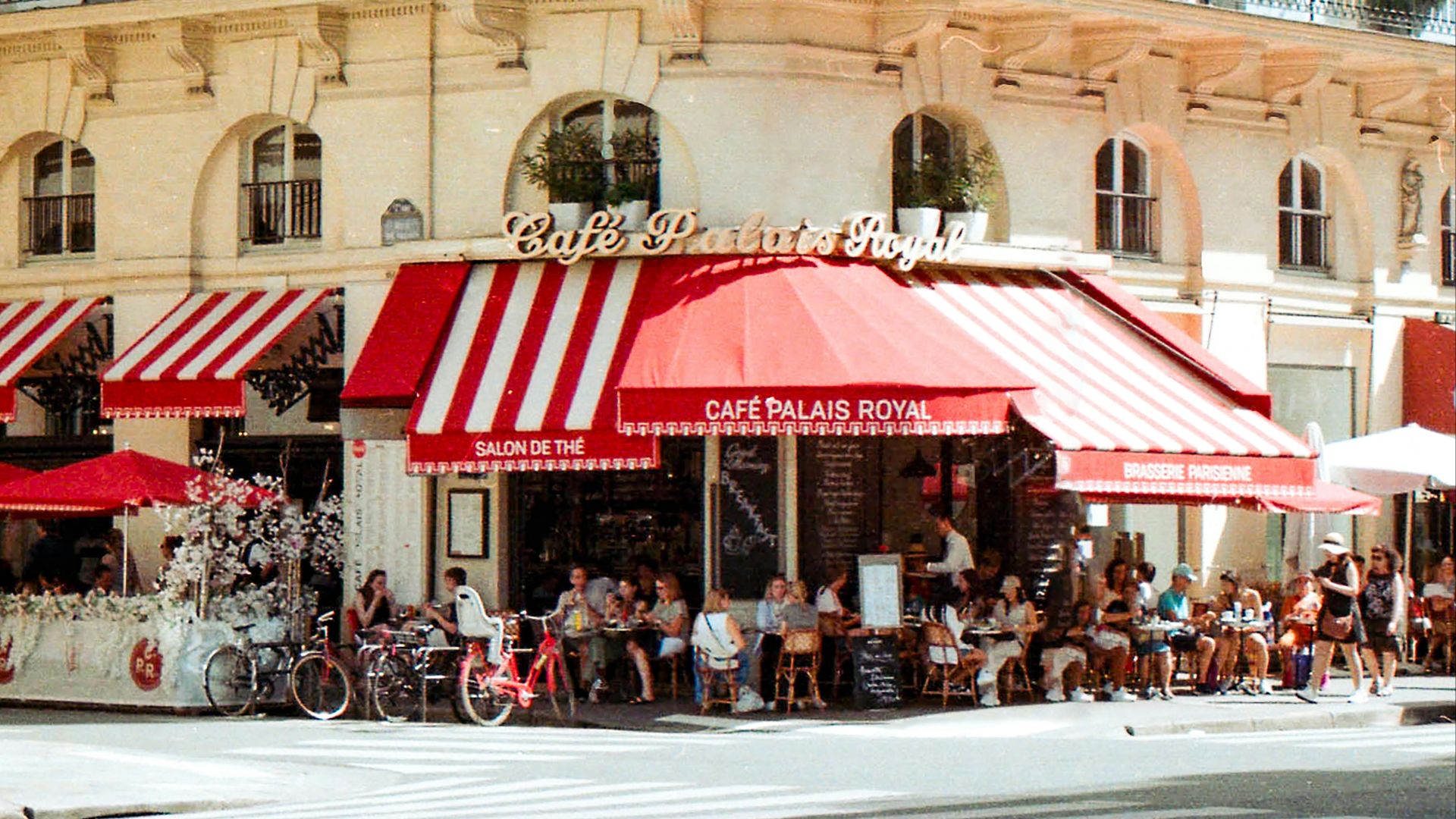 A bustling scene at Café Palais Royal in Paris with patrons enjoying a sunny day.
