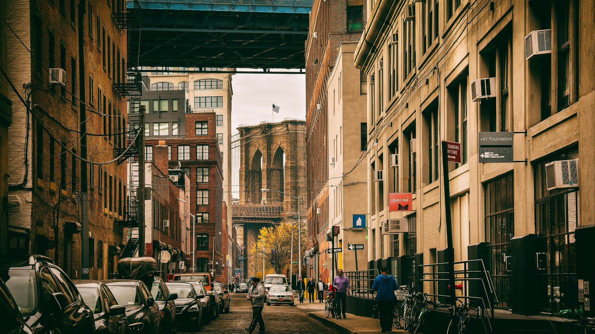 Urban view of a Brooklyn street under the bridge with city life and architecture.