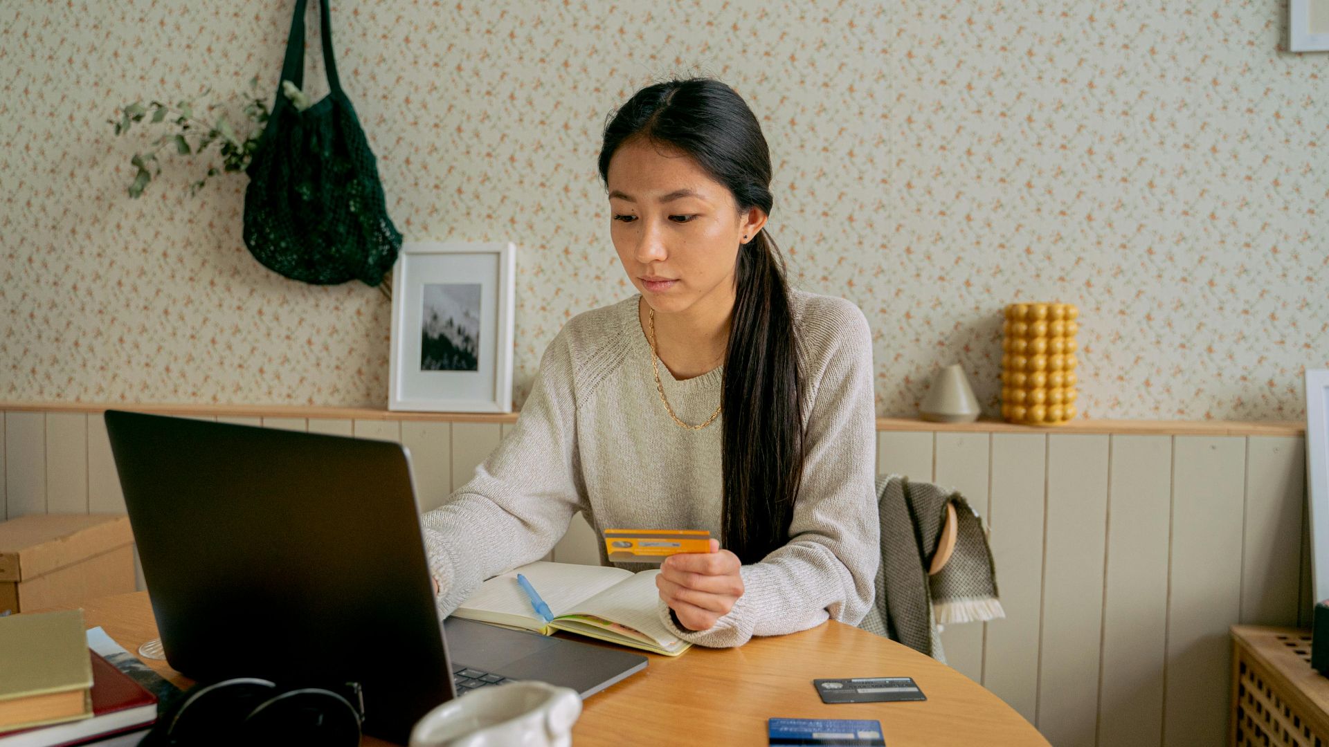 A woman using a laptop and credit card for online shopping at a cozy indoor setting.