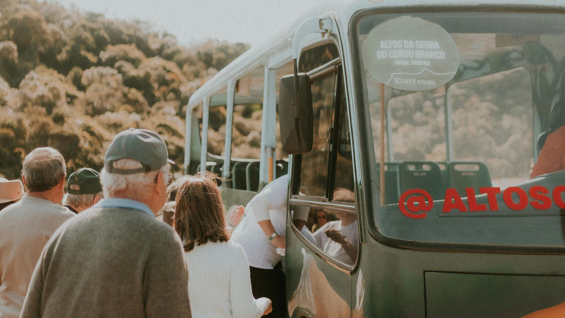 Group of people boarding a bus surrounded by nature, showcasing travel and transportation.