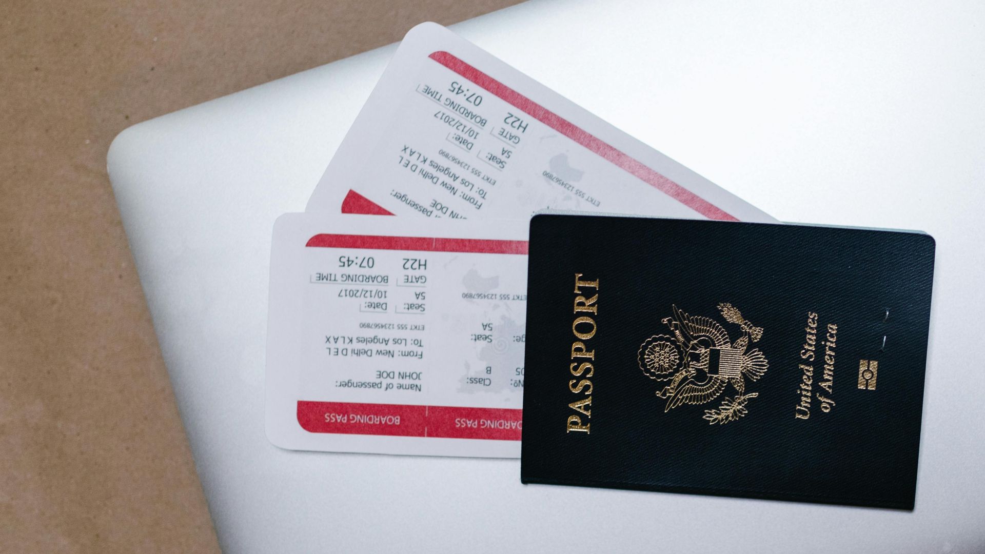 Close-up of a passport and boarding passes on a laptop, symbolizing travel preparation.