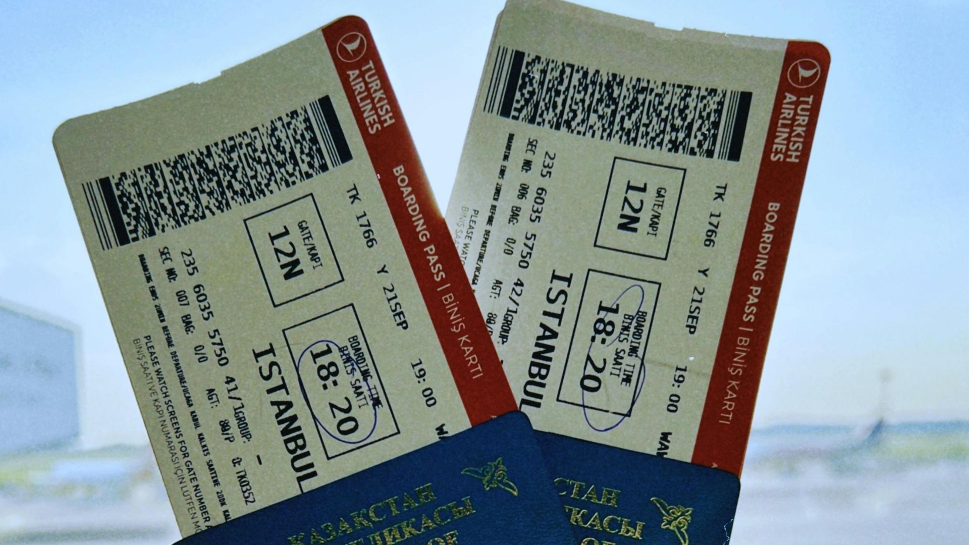 A Kazakhstan passport holds two airline tickets against an airport backdrop in Warsaw, Poland.
