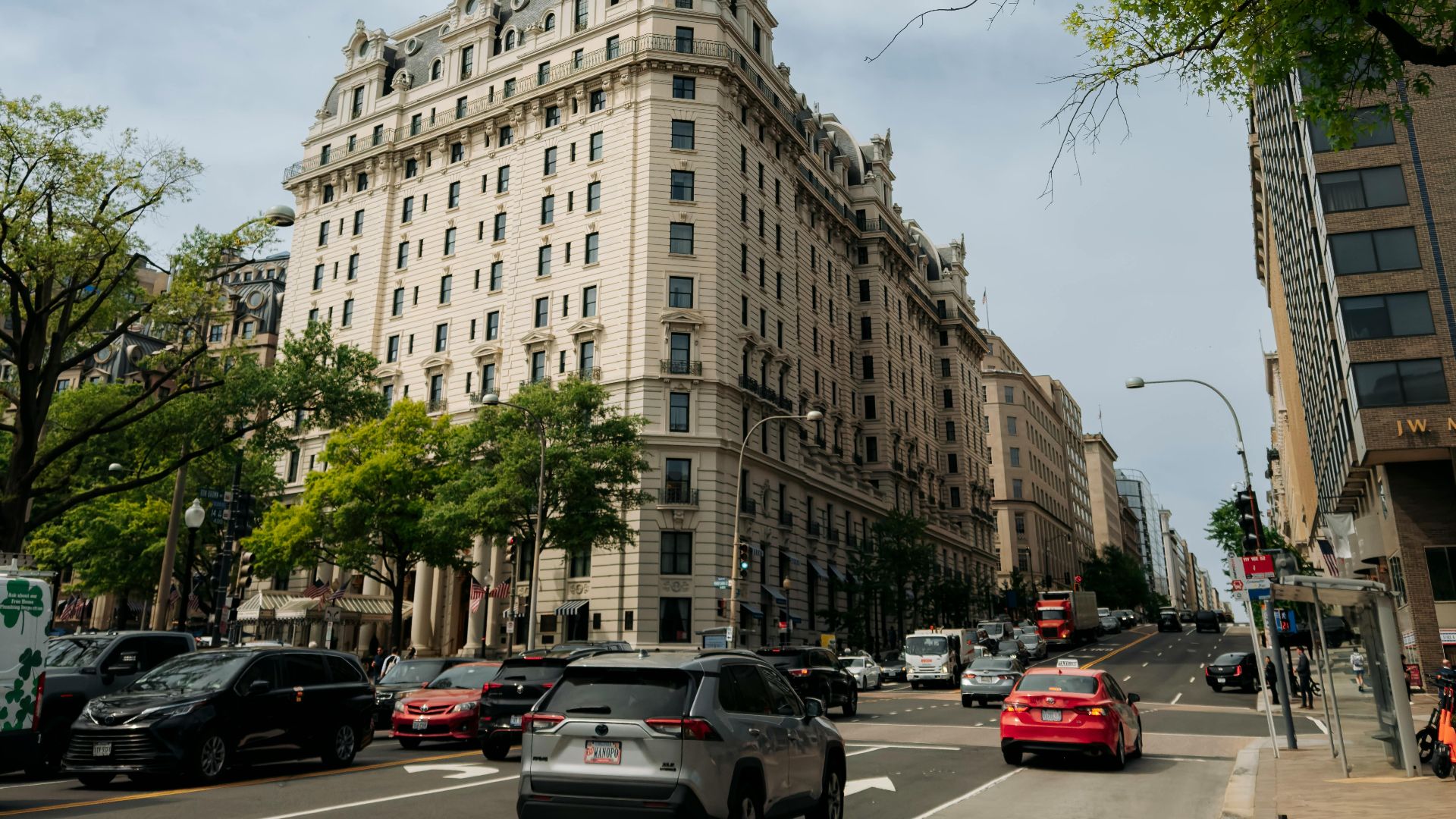 A bustling street scene featuring historic architecture in Washington, DC, with trees and traffic.