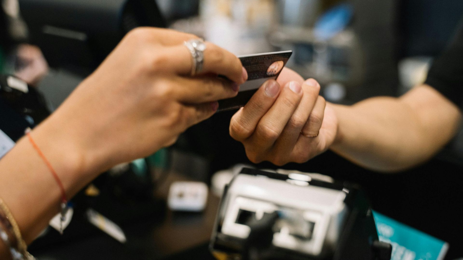 Close-up of hands completing a payment transaction at a retail checkout using a bank card.
