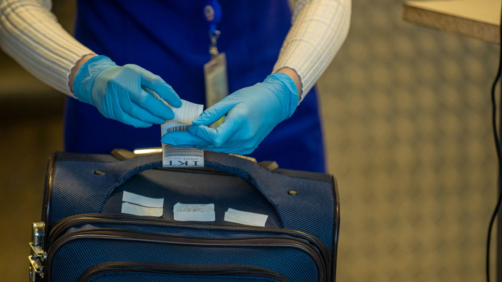 Close-up of airport security process with gloved hands inspecting luggage tags.