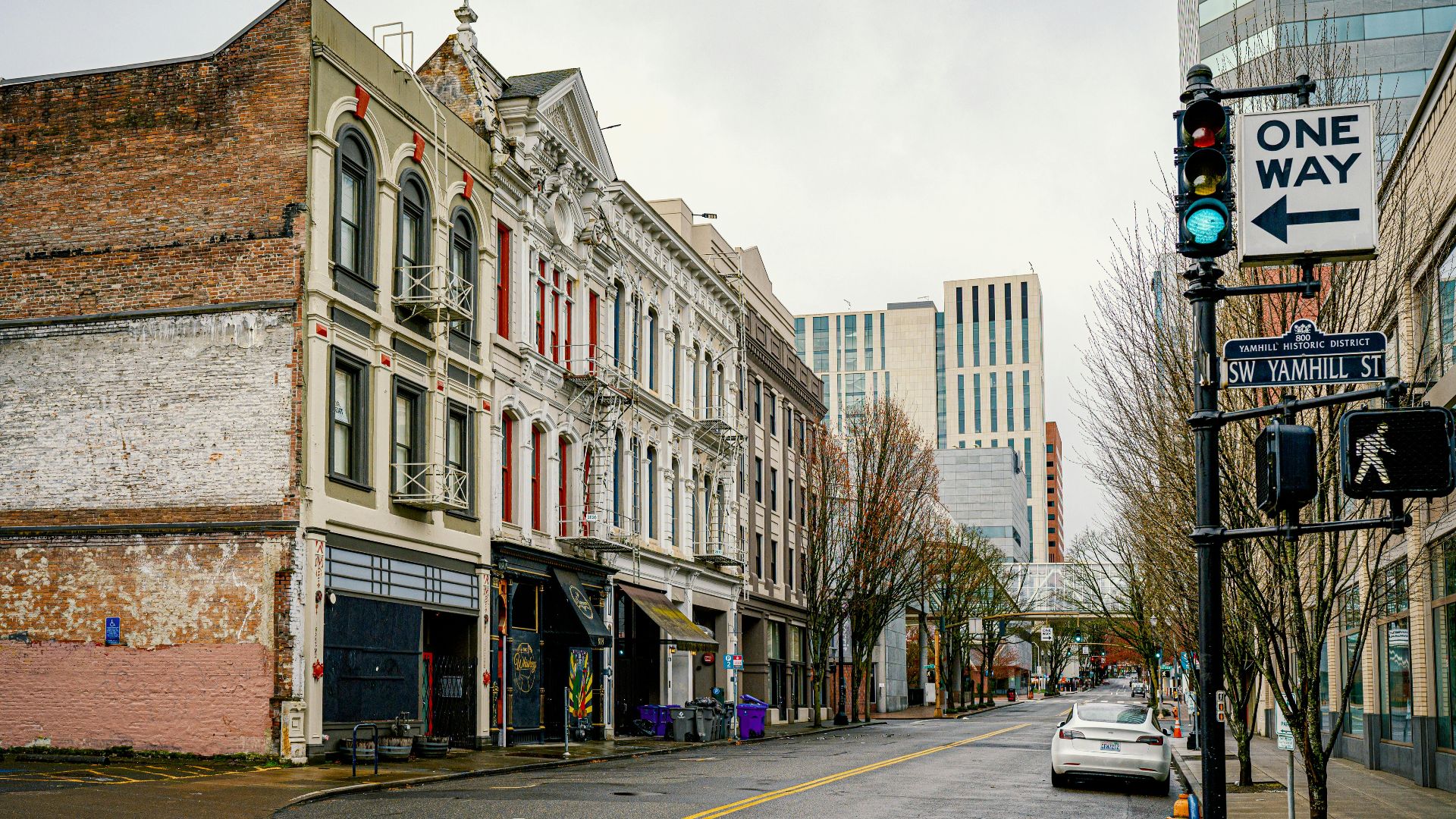 A rainy street view of Portland's Yamhill Historic District with historic and modern buildings.