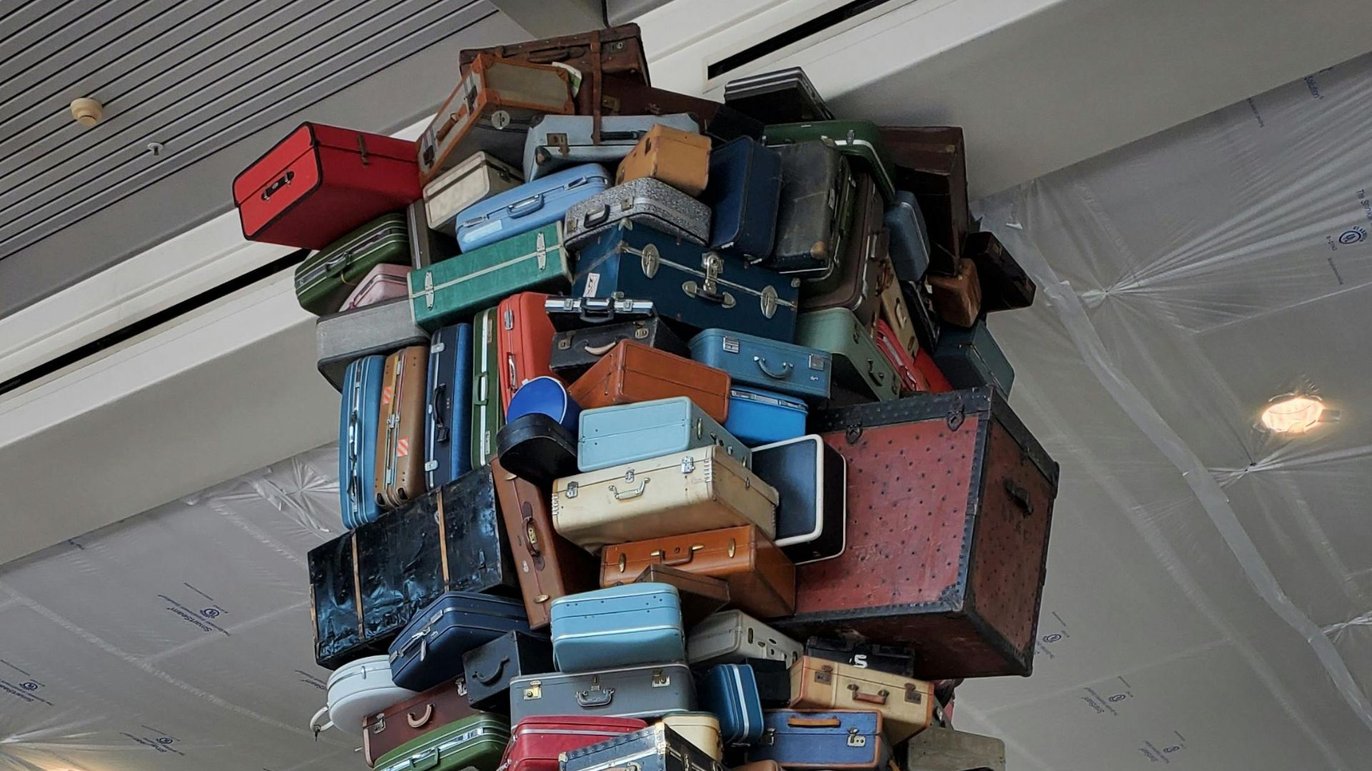 Artistic sculpture of a large pile of suitcases in an airport terminal.