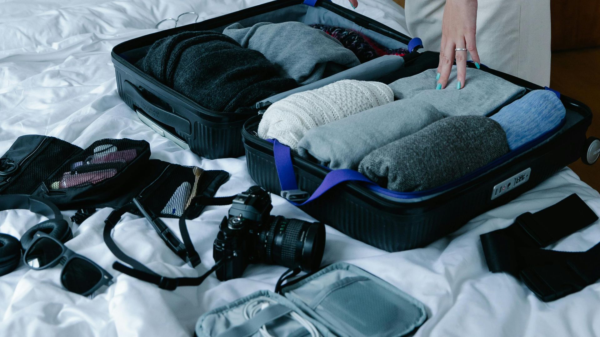 Woman packing neatly organized suitcase on bed for travel preparation.