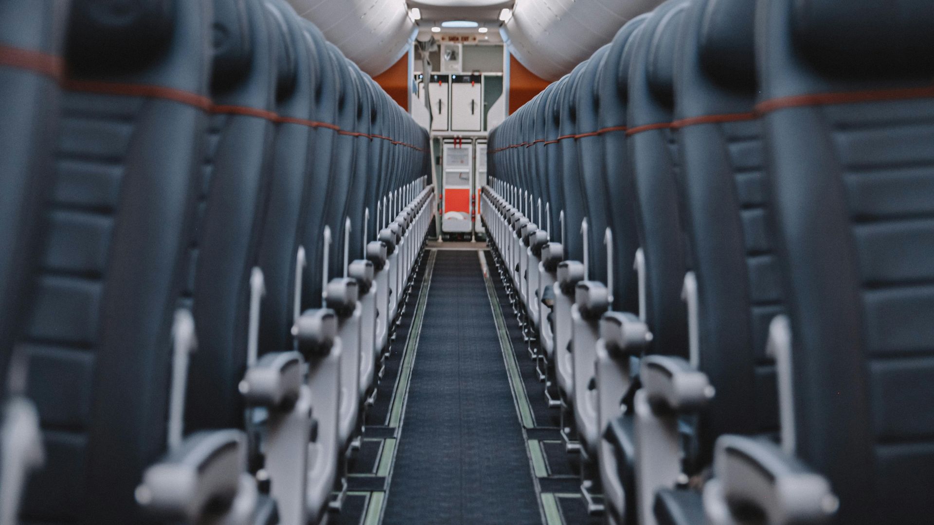 View down the aisle of an empty airplane cabin showcasing seats and overhead compartments.