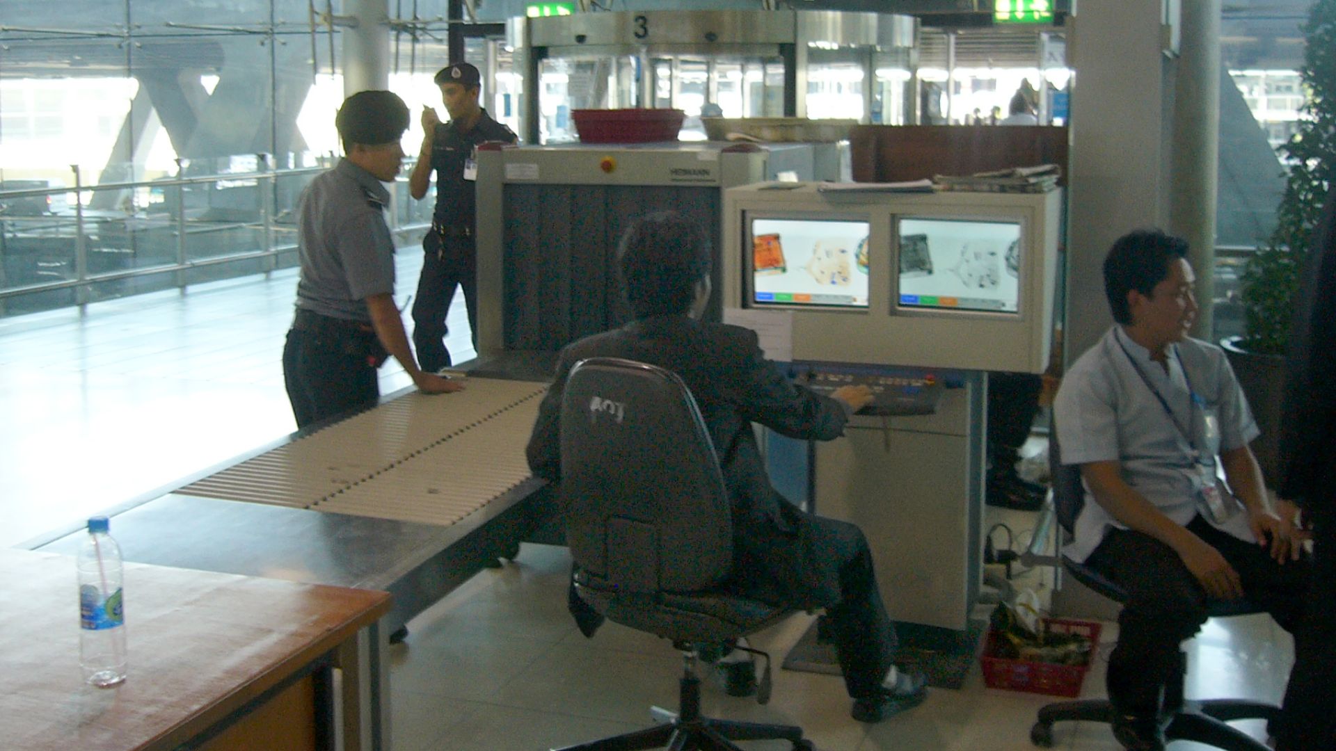 Luggage screening device at Suvarnabhumi International Airport, Bangkok, Thailand. This security post is located for entering the airport which means all people (visitors and passengers) have to pass such a control. Another control will be for boarding luggage before entering the secured area (passengers only). View towards the street.