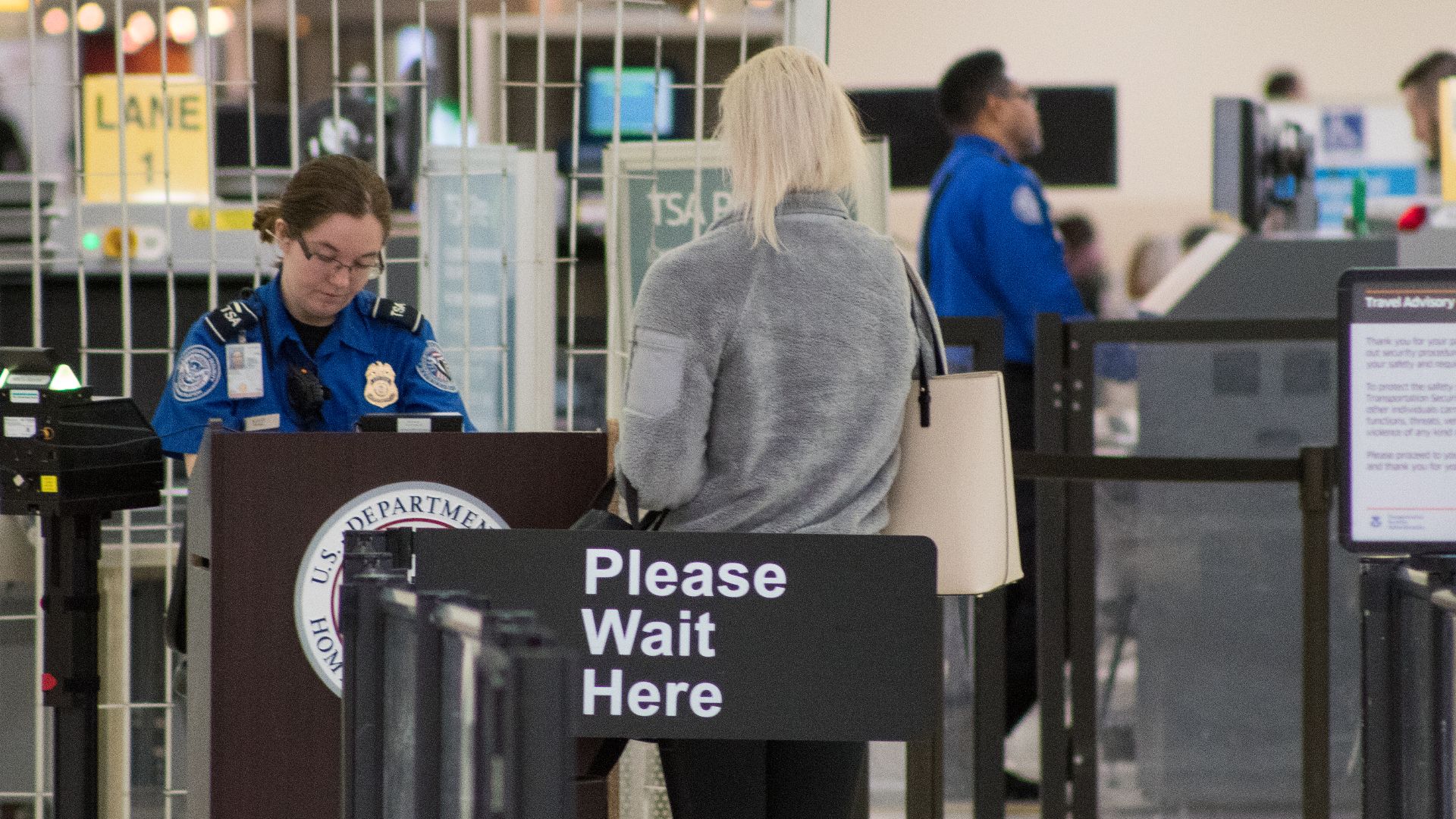 A Transportation Security Administration agent at a checkpoint verifying passenger identification, John Glenn Columbus International Airport