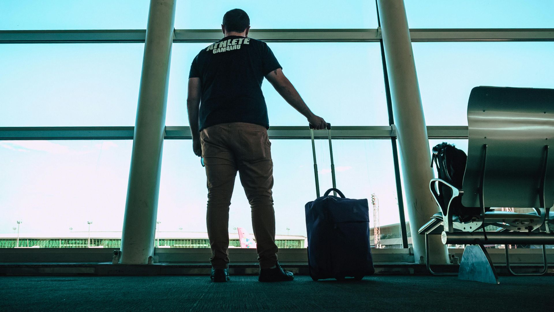 Man with luggage waiting at airport lounge, anticipating departure in a modern setting.