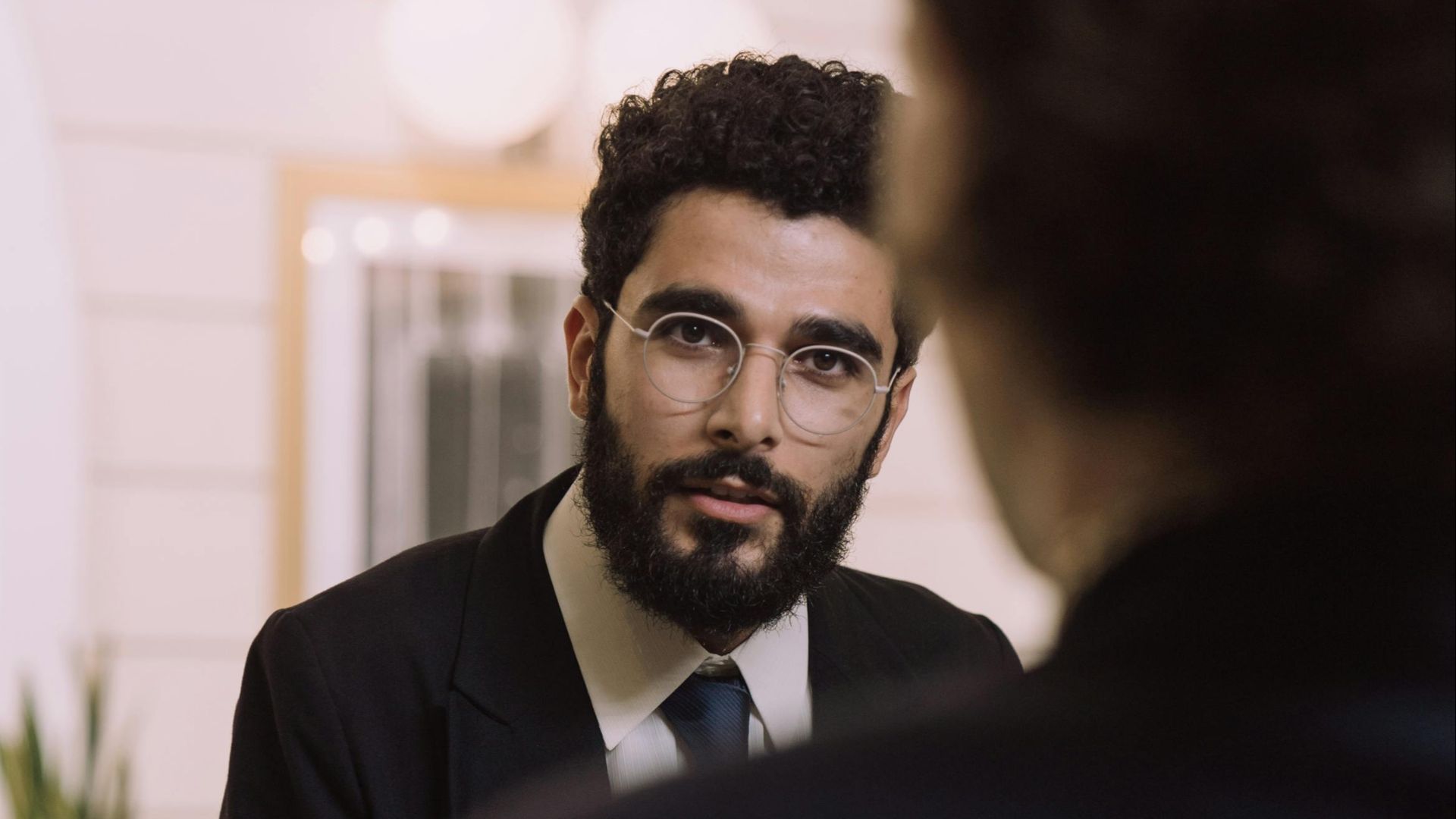 A professional businessman checks in at a hotel reception, engaging with a concierge.