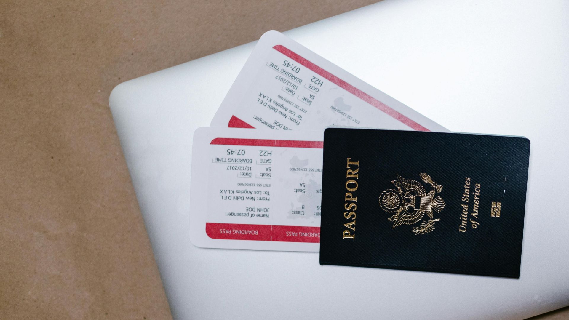 Close-up of a passport and boarding passes on a laptop, symbolizing travel preparation.