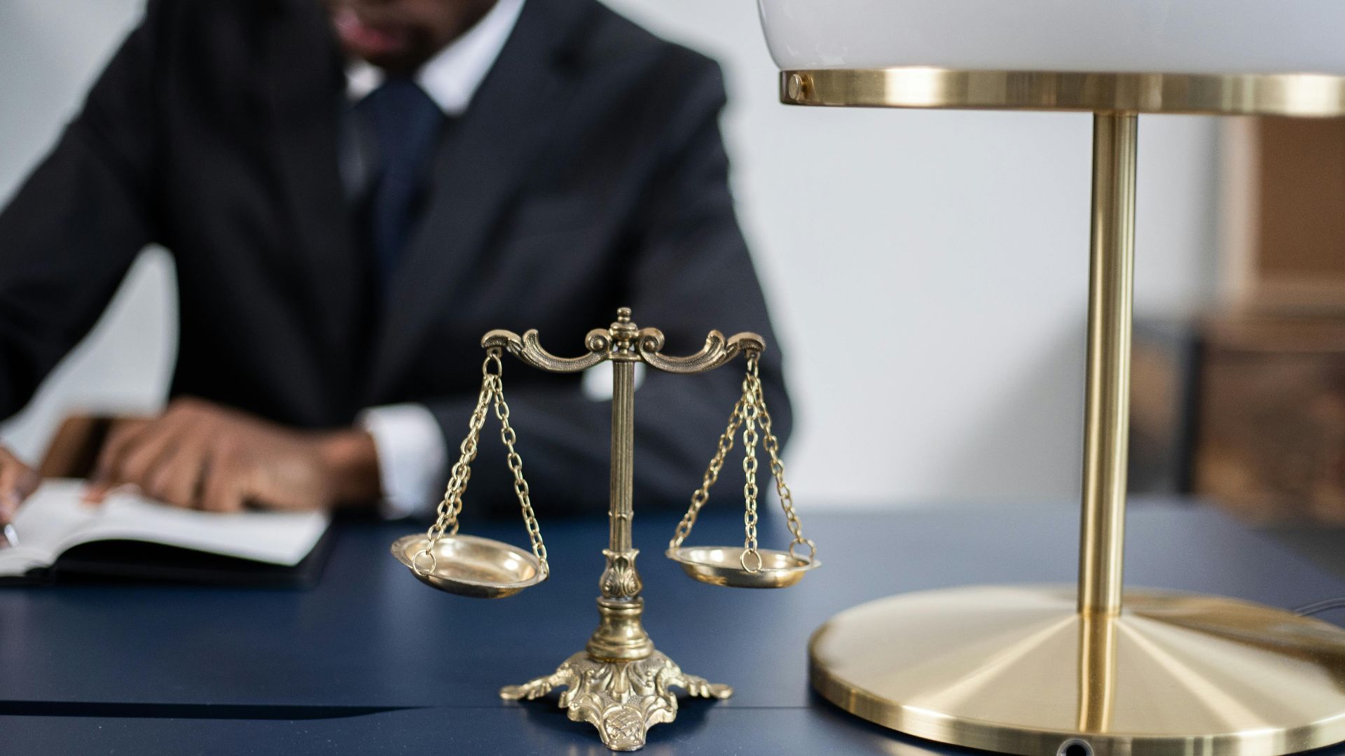 Elegant legal office with a close-up of golden scales of justice on a sleek dark desk.