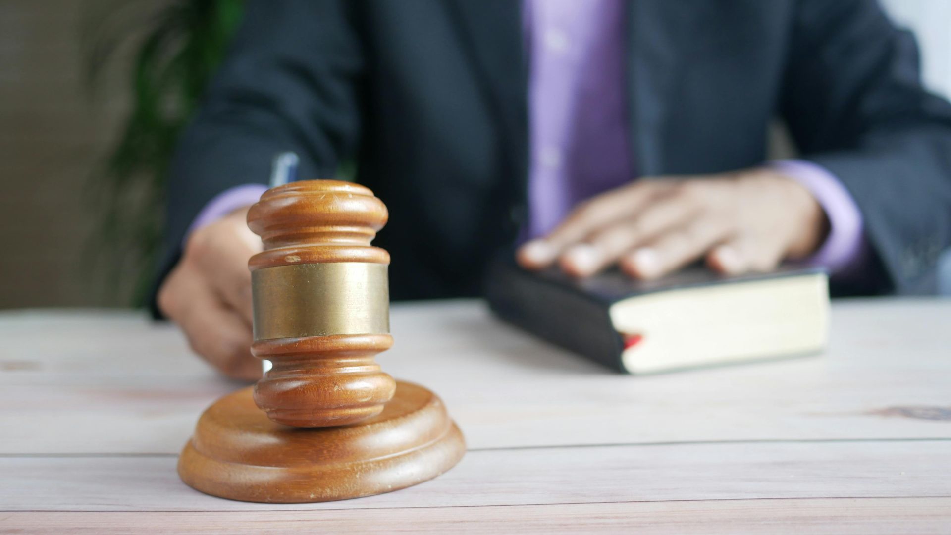 A wooden gavel and legal book represent justice in a court setting, emphasizing order and legal authority.