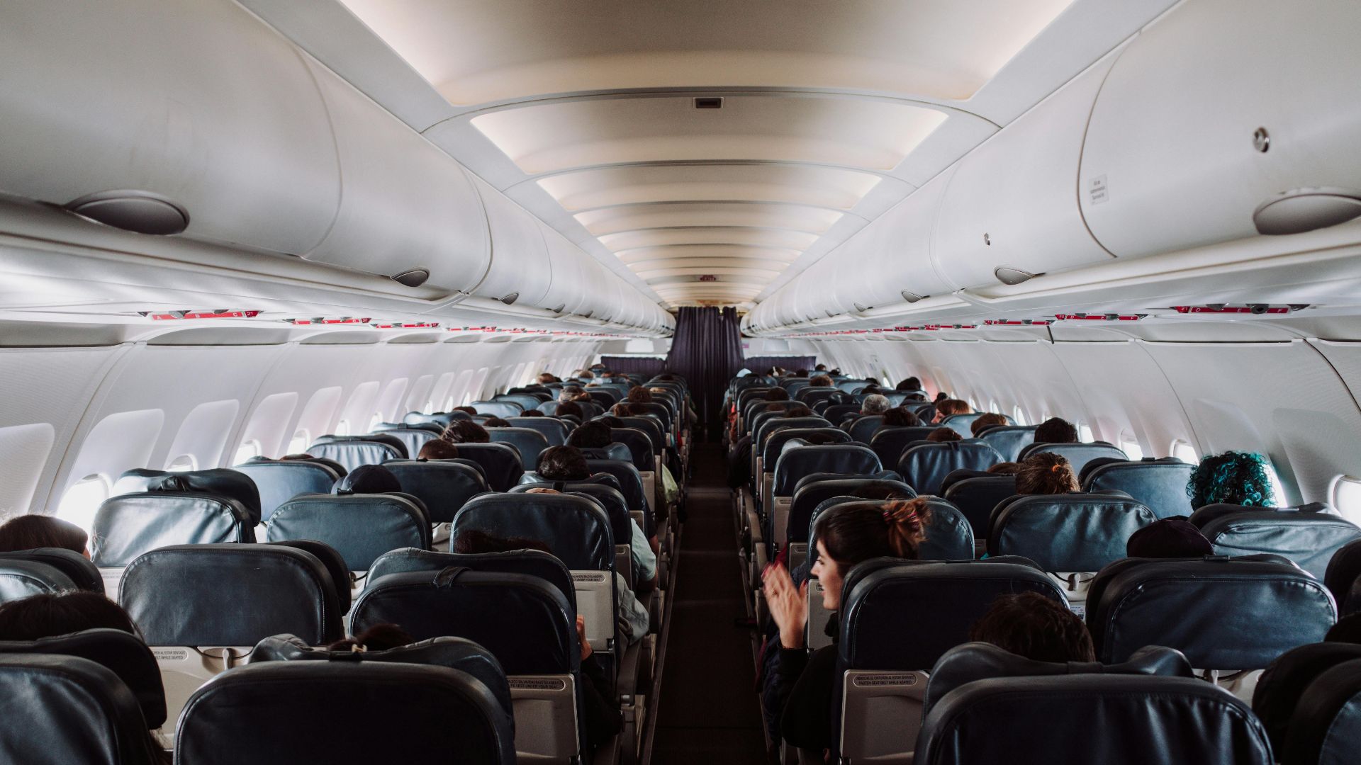 A view of passengers seated inside a commercial airplane cabin during flight.
