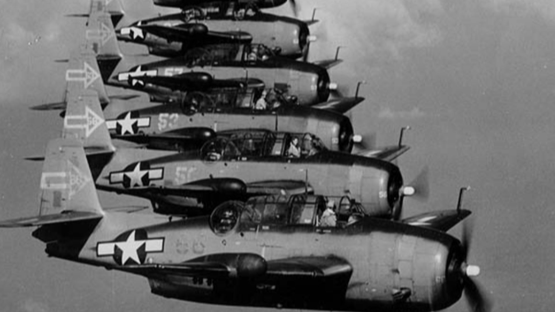 Seven Grumman TBM-3D Avenger bombers of night torpedo squadron VT(N)-90 flying in formation in January 1945. The squadron was part of Night Air Group 90 on the carrier USS Enterprise (CV-6). Note radar pods in right-side wings, and the distinctive tail insignia.