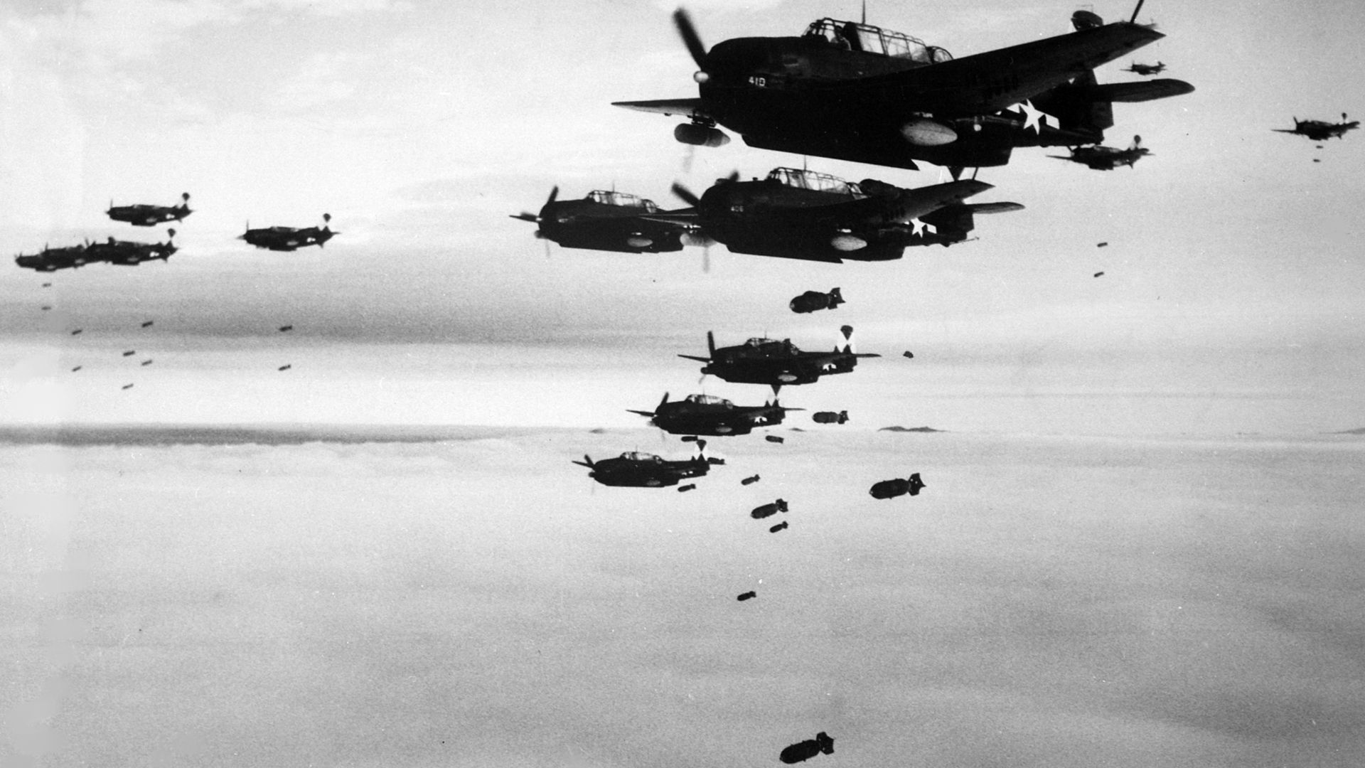 U.S. Navy Grumman TBM-3 Avengers and Curtiss SB2C Helldivers assigned to Carrier Air Group 83 (CVG-83) aboard the aircraft carrier USS Essex (CV-9) dropping bombs on Hakodate, Japan, in July 1945.