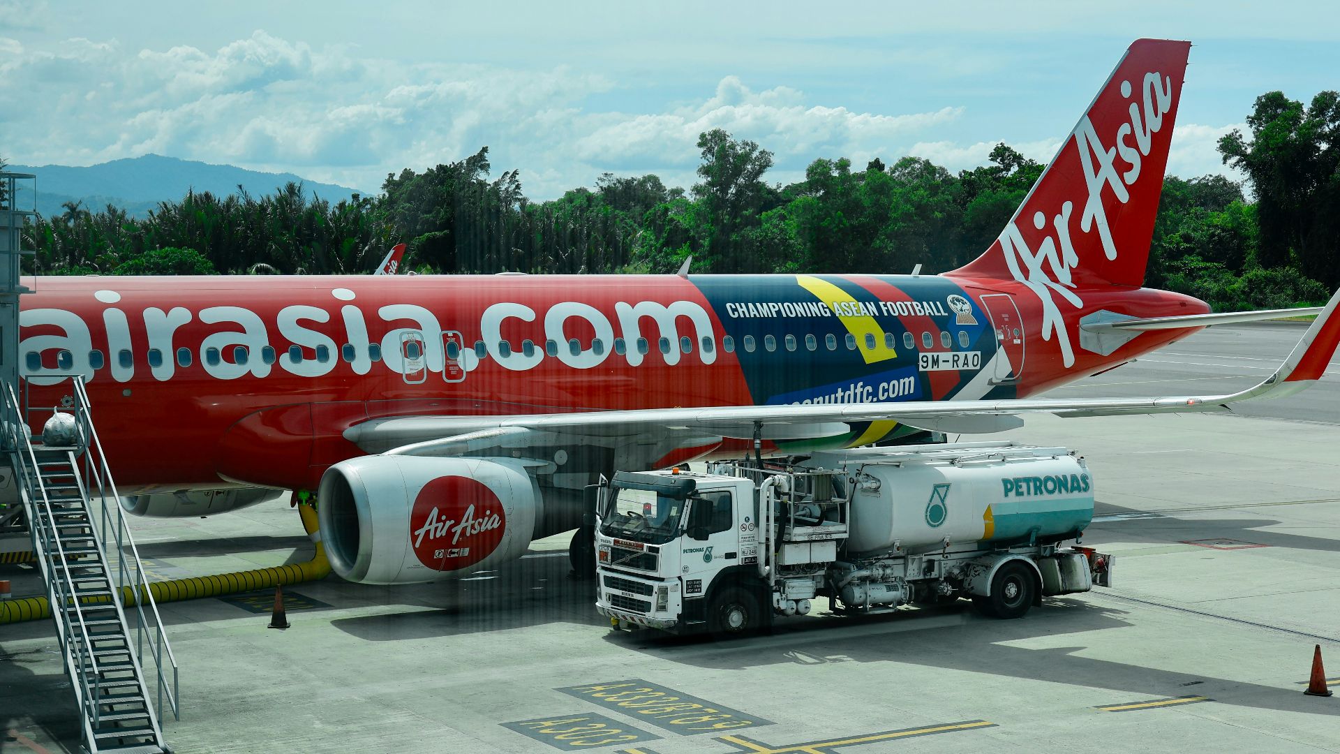 Airasia airplane being refueled at an airport tarmac.