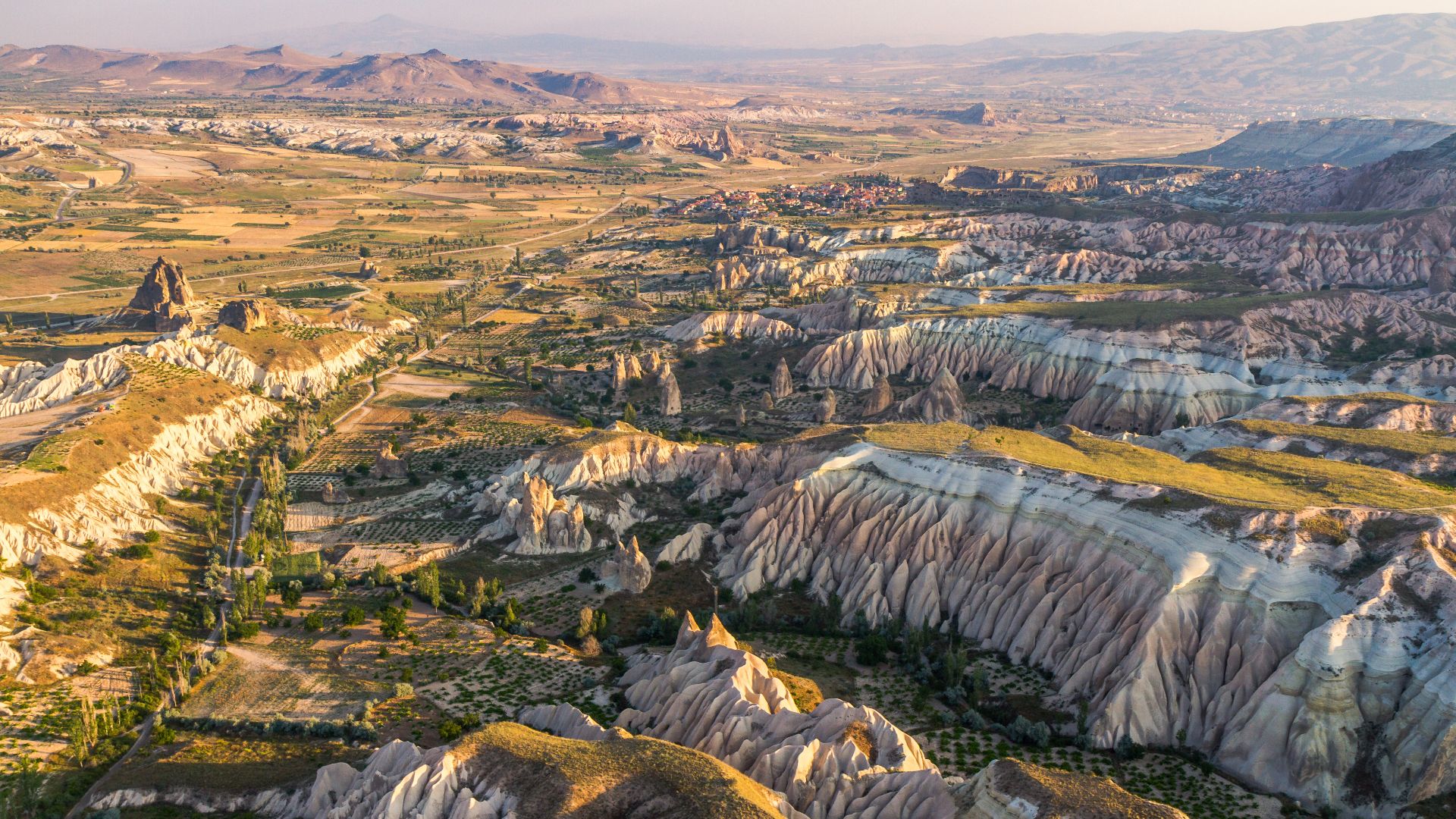 Aerial view over Cappadocia, nearby Gorëme, Turkey. Features from very far top to bottom, the city of Avanos, its small village Çavusin and the rose and red valleys (Güllüdere and Kizilçukur valleys)