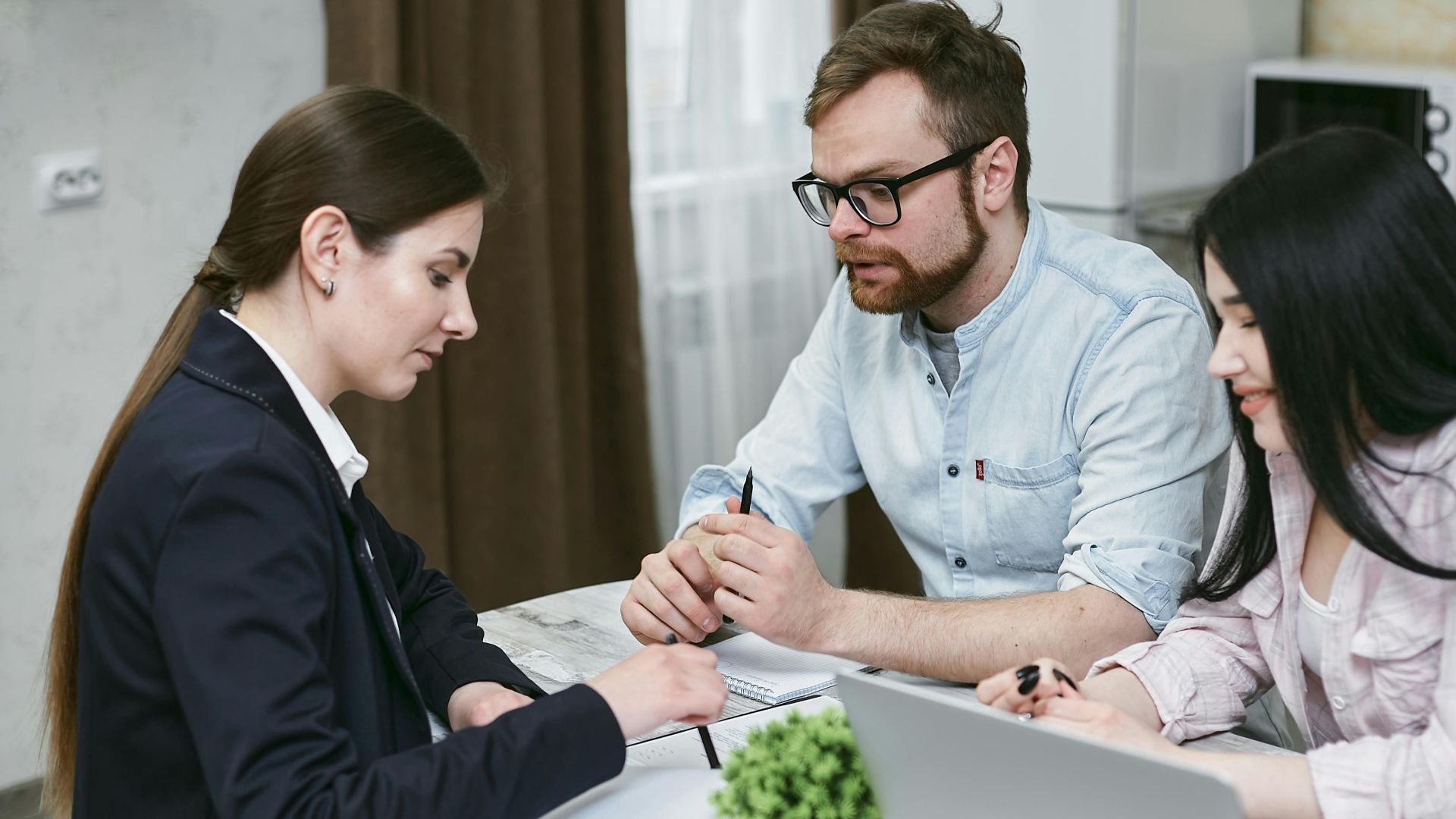 A couple discusses financial documents with their advisor, highlighting investment strategies.