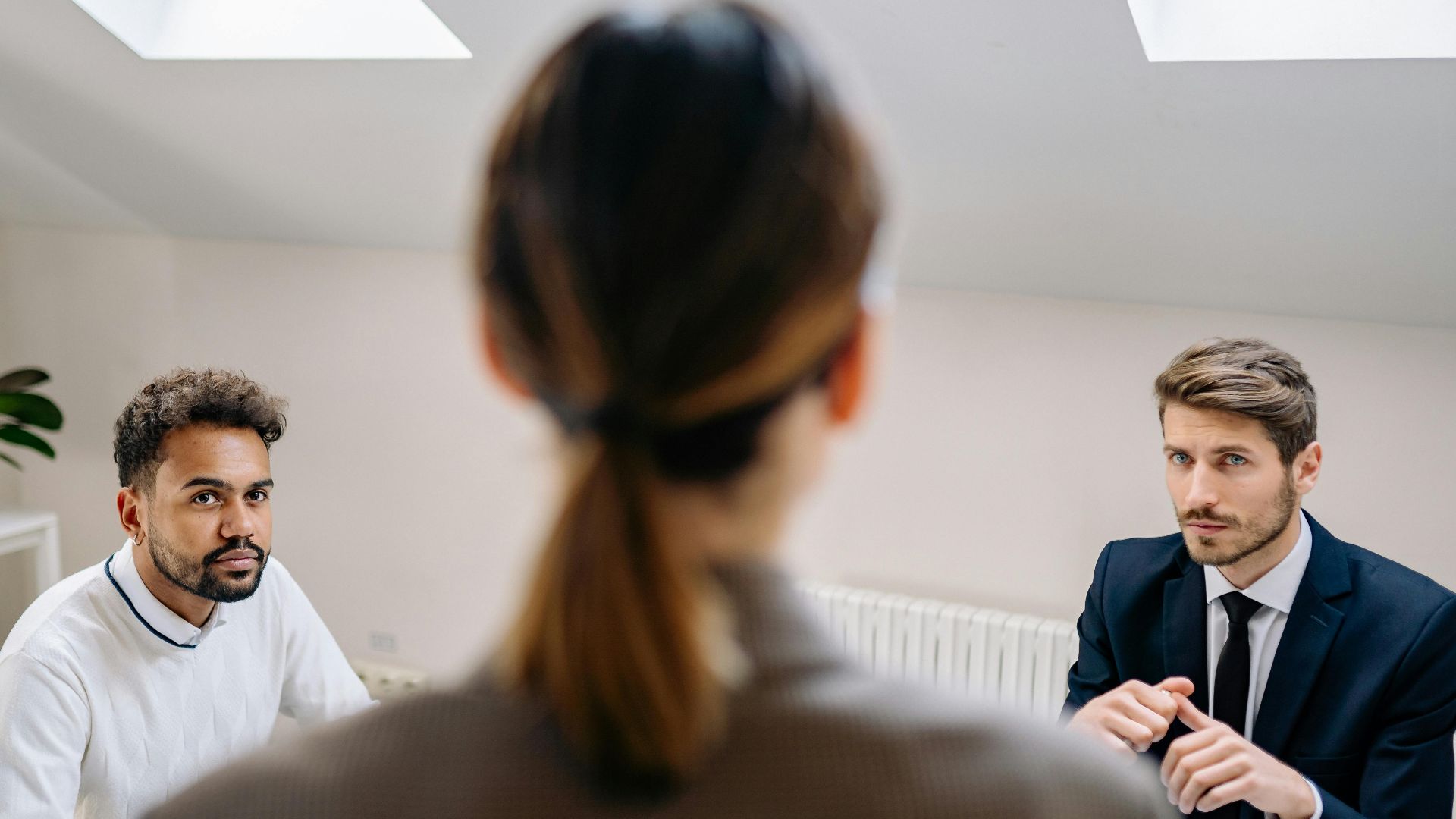 A professional business meeting involving three adults in a modern office setting.
