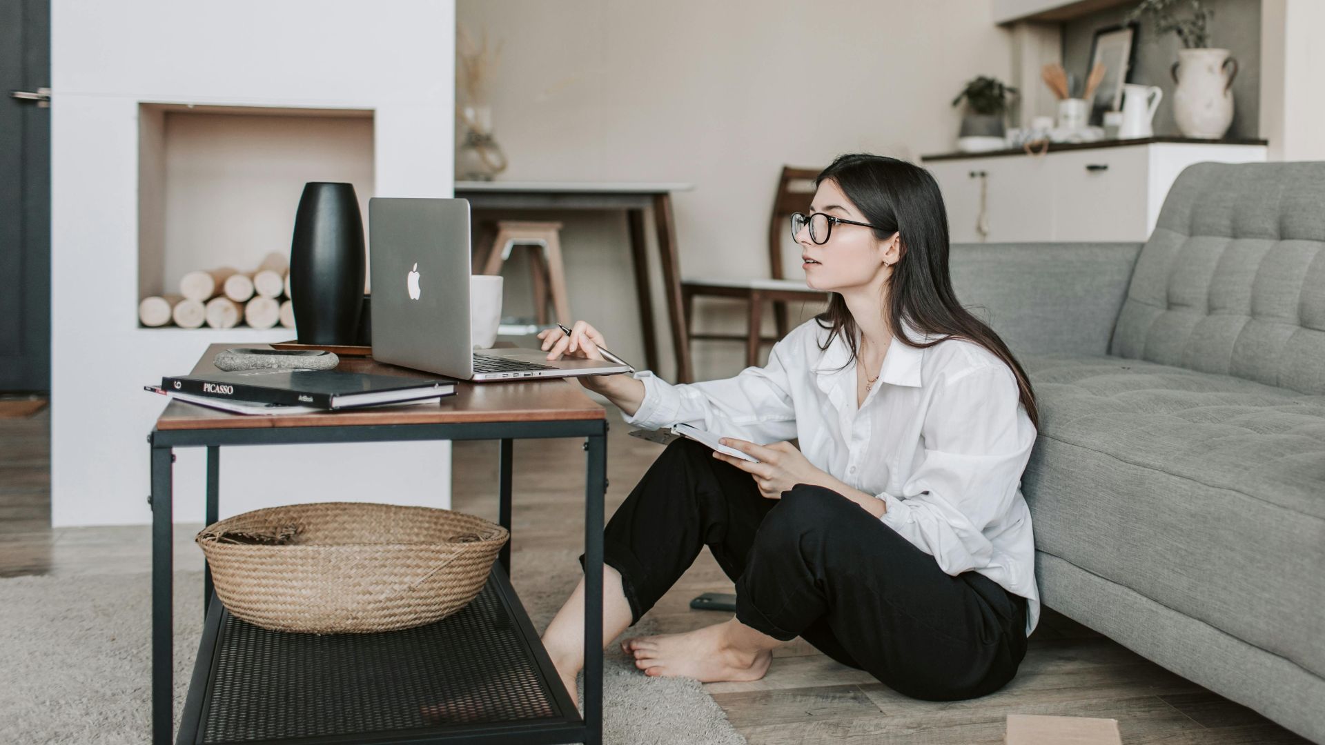 Asian woman working on laptop from cozy living room, showcasing modern home office setup.