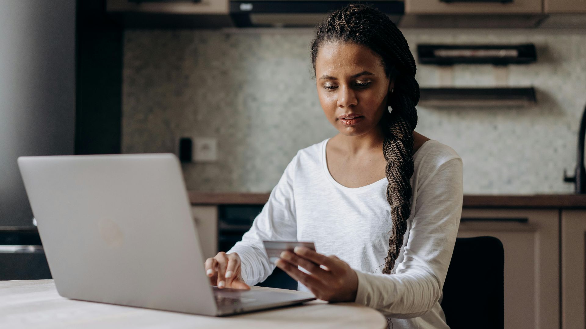 African American woman using laptop and credit card for online shopping at home.