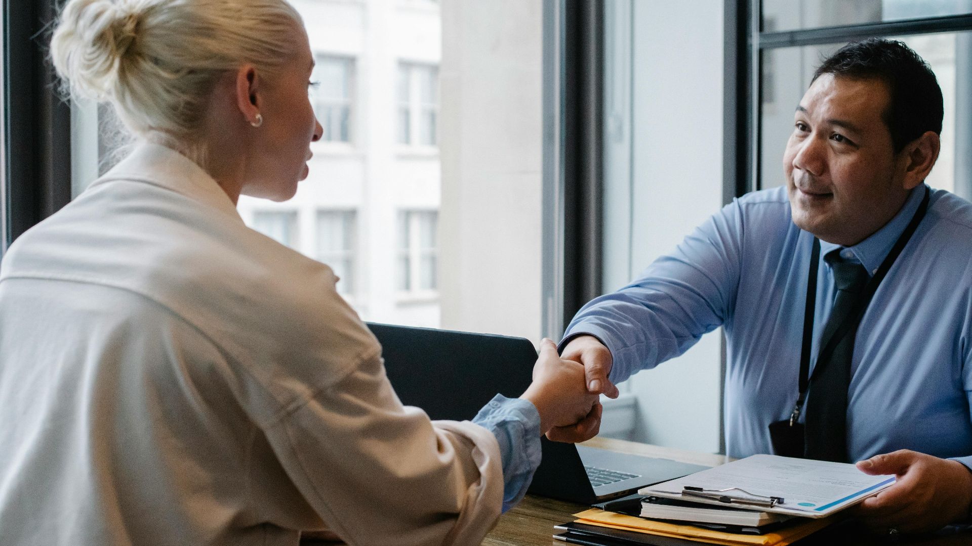 Ethnic male entrepreneur shaking hand of female candidate during job interview in business company