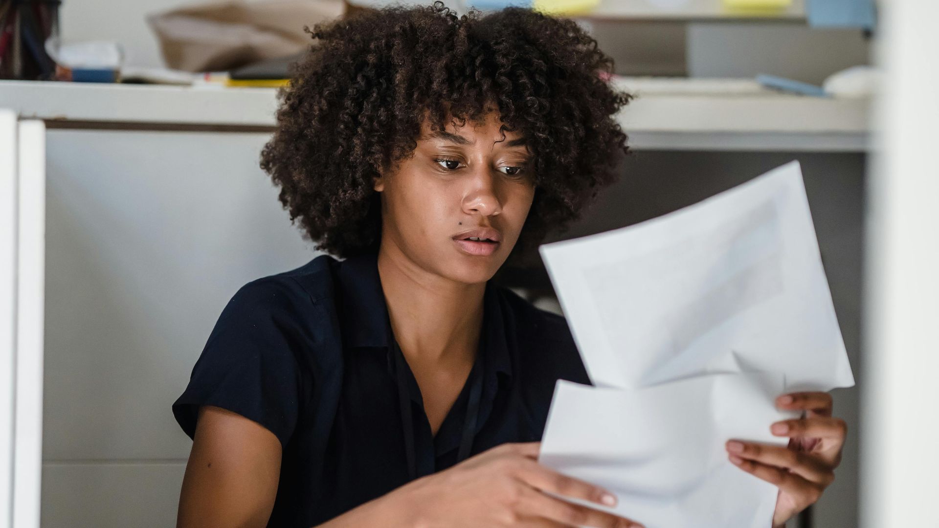An African American businesswoman reviewing documents on the office floor.