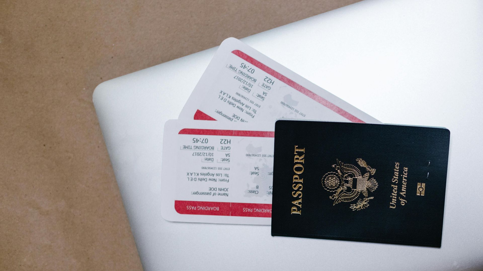 Close-up of a passport and boarding passes on a laptop, symbolizing travel preparation.