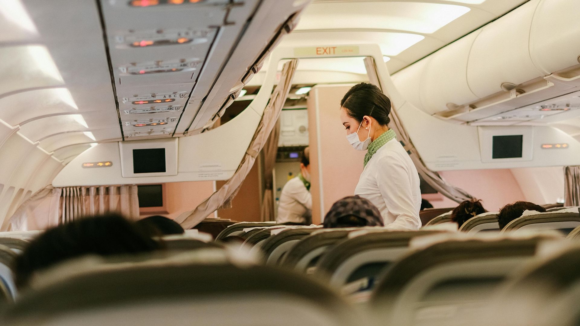 Flight attendant serves passengers in an airplane's cabin interior, focusing on customer service during air travel.