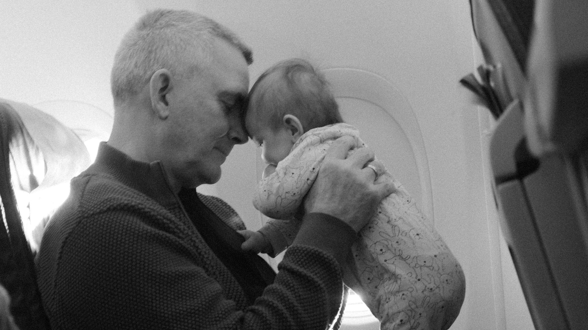 A heartwarming black and white photo of a man tenderly holding a baby on an airplane.
