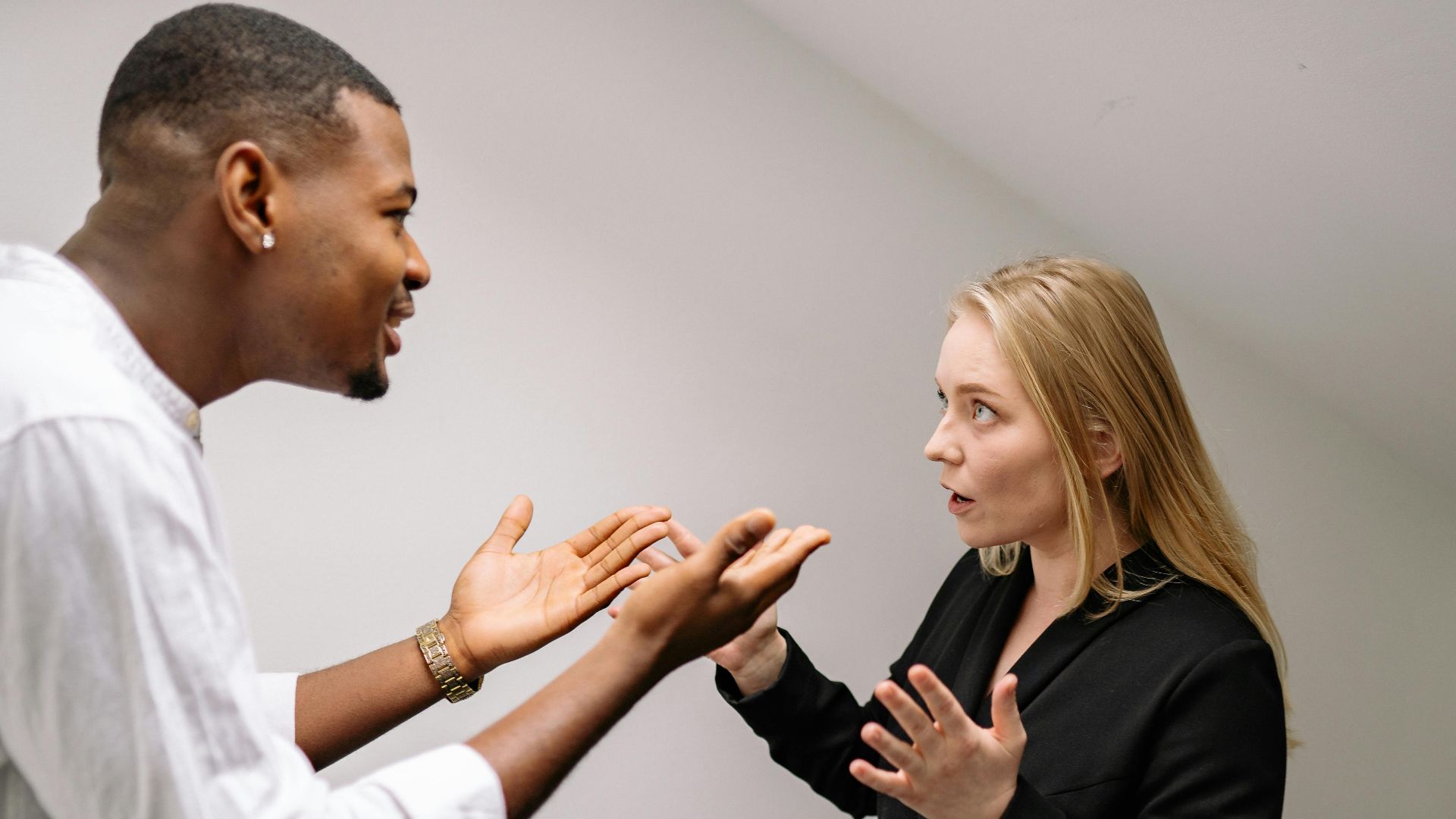 A man and woman having a heated discussion in a minimalistic indoor space.