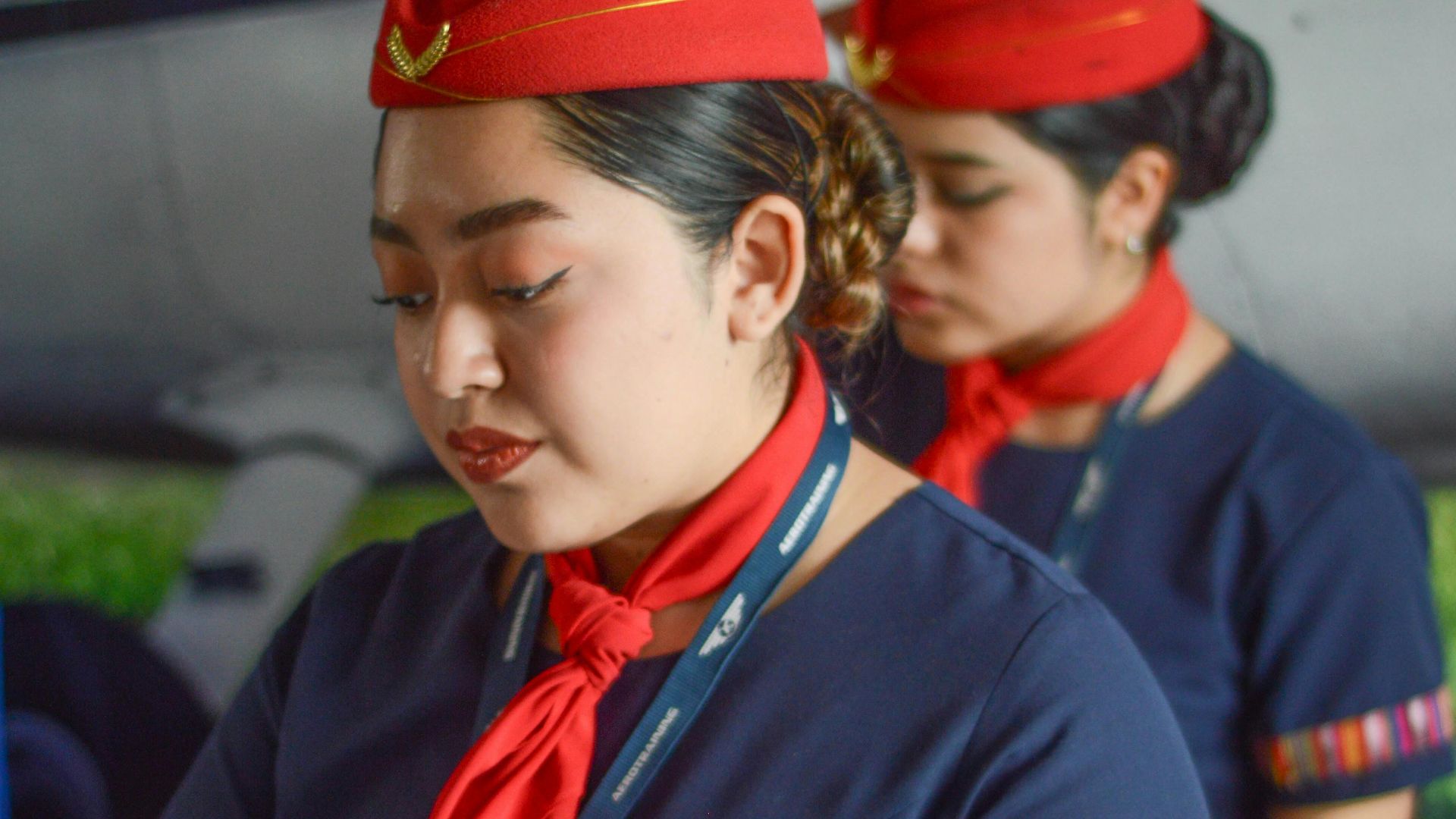 Two flight attendants in elegant uniforms reading onboard an aircraft.