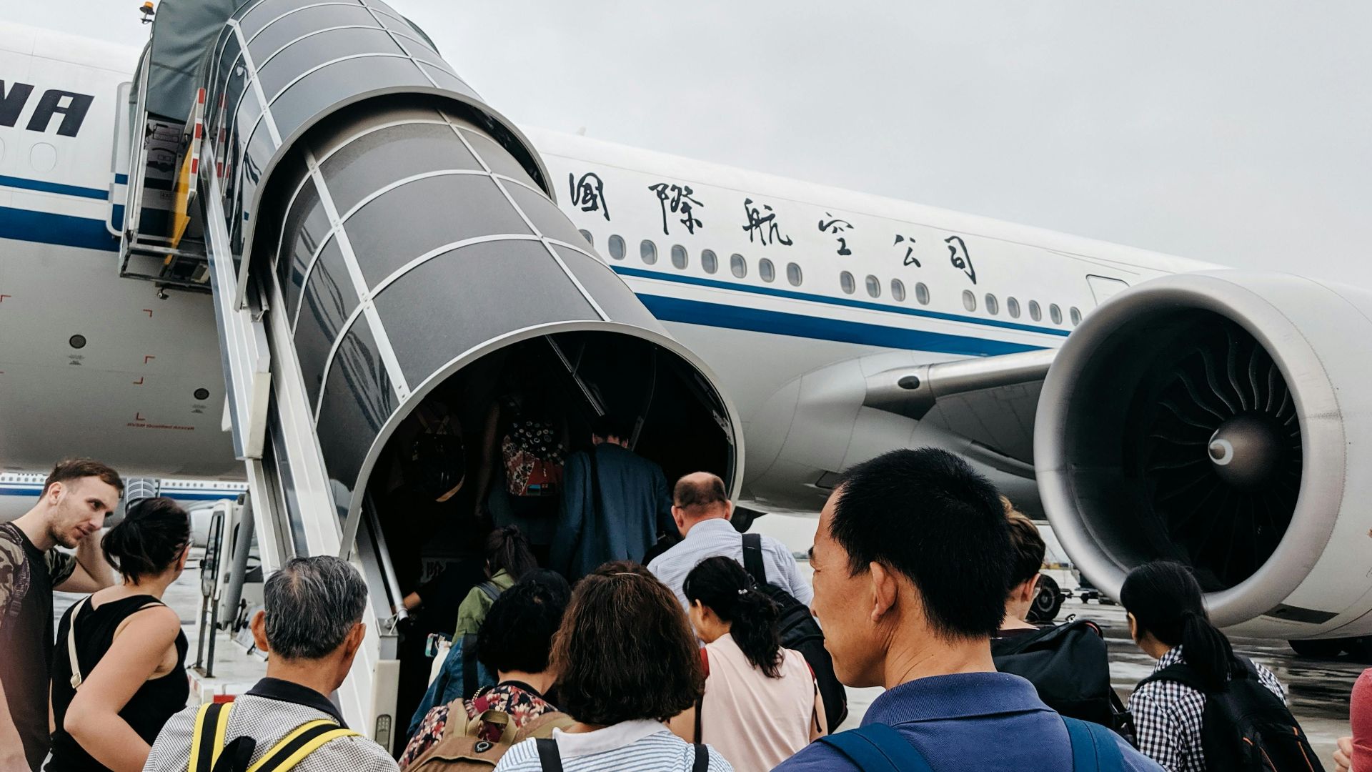 A group of people boarding an airplane via a jet bridge at Beijing Airport, China.