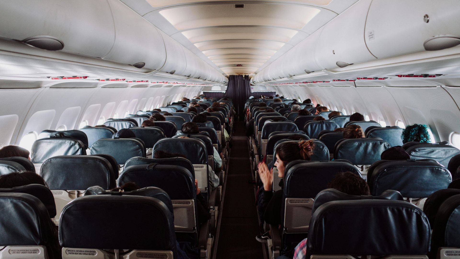 A view of passengers seated inside a commercial airplane cabin during flight.