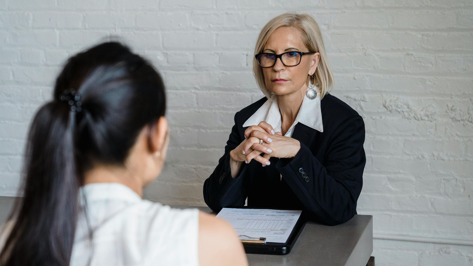 Professional businesswoman in a black blazer conducting an interview indoors.