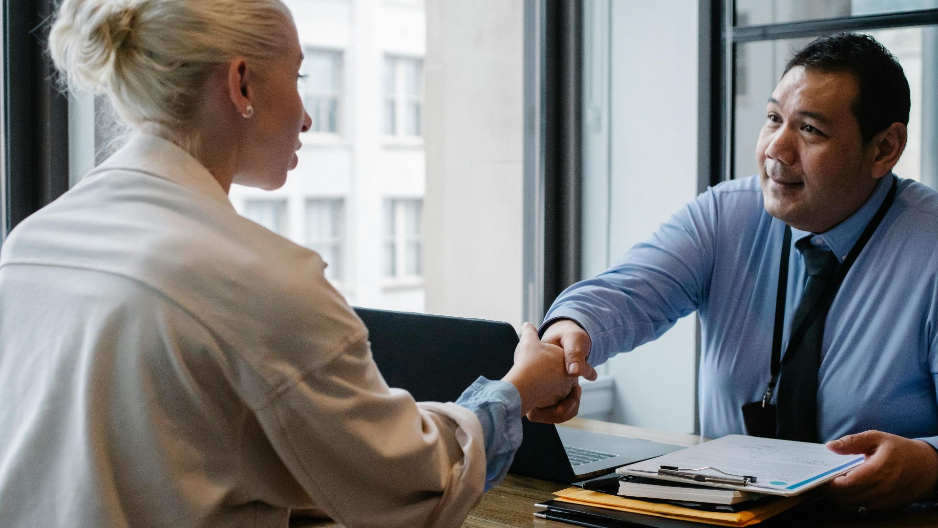 Ethnic male entrepreneur shaking hand of female candidate during job interview in business company