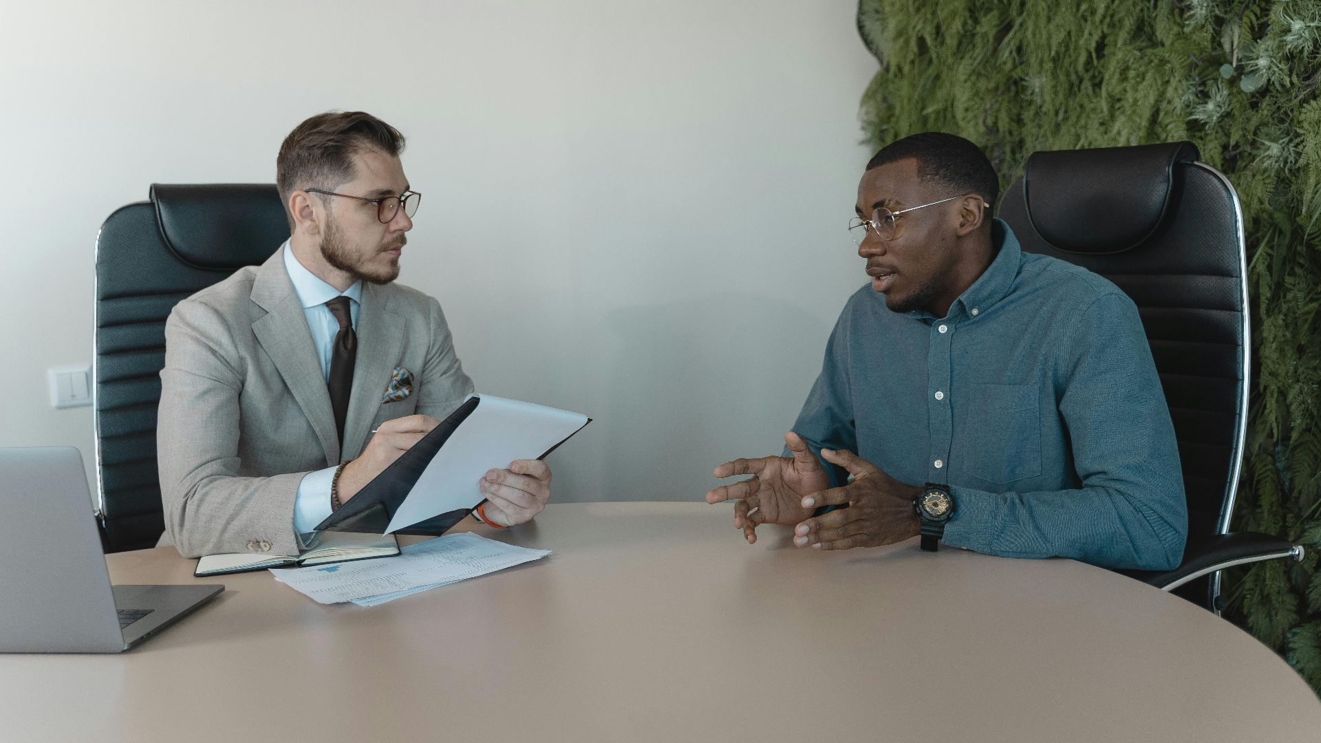 Two businessmen engaged in a discussion during a job interview in a contemporary office environment.