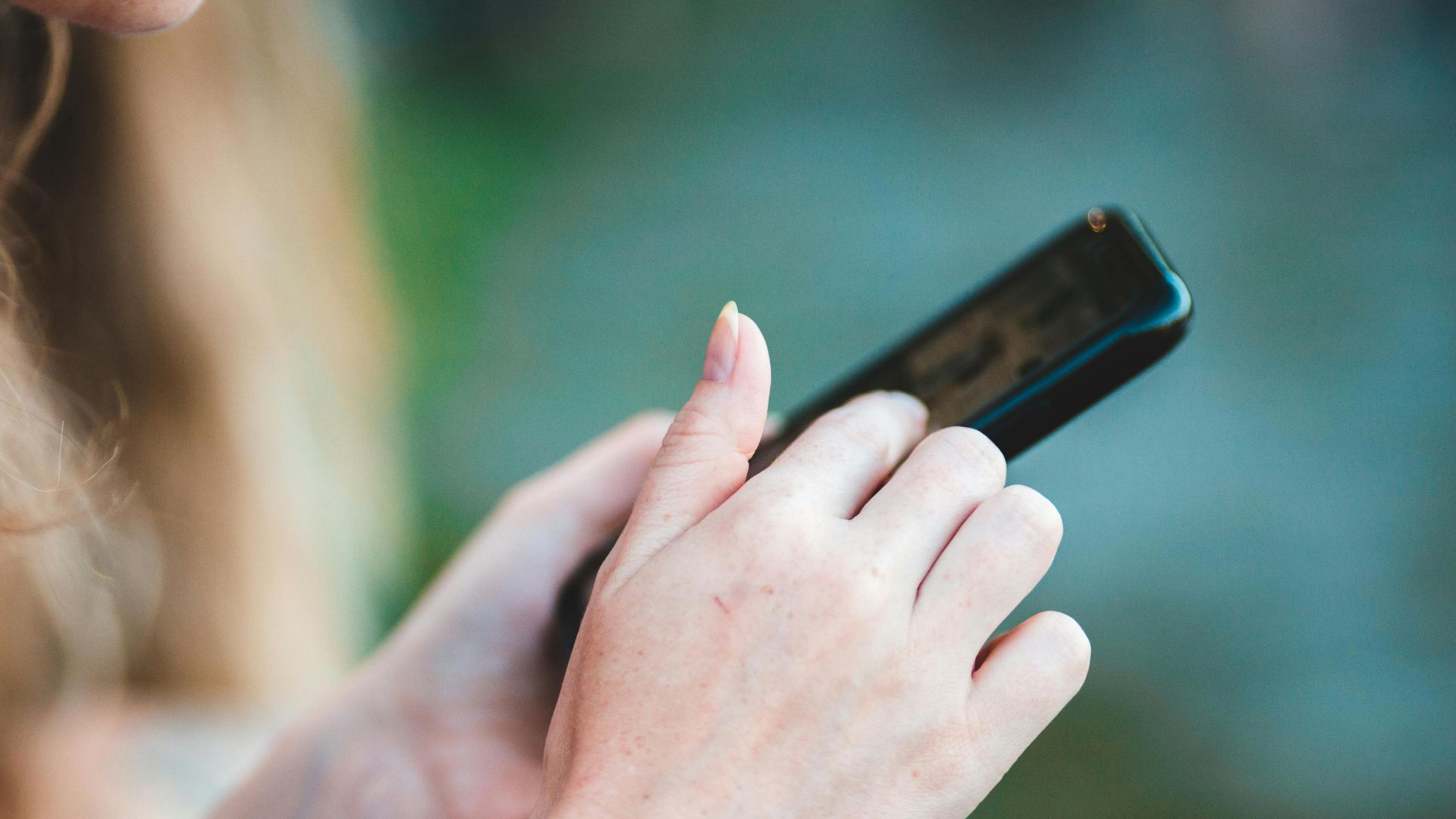 Hands holding a smartphone with blurred background, showcasing modern technology use.