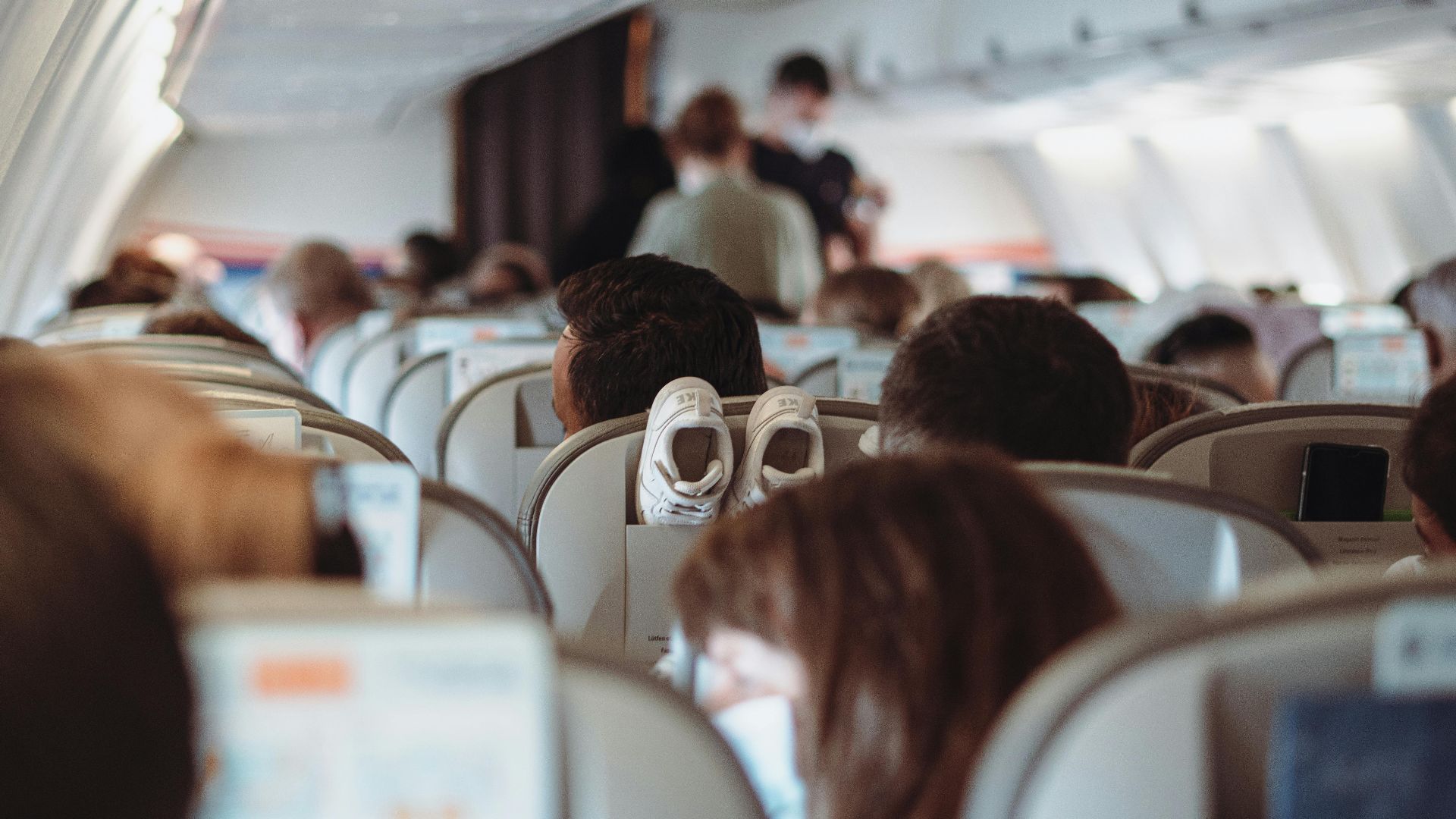 View of passengers wearing masks and seated in economy class during flight.