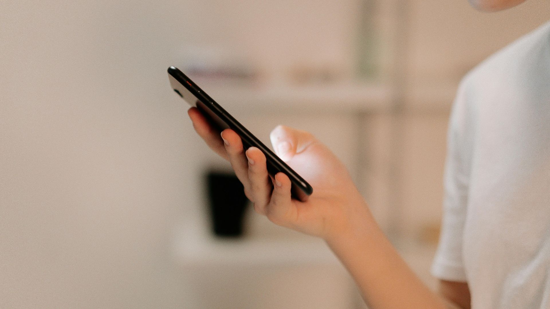 Close-up of a person using a smartphone indoors, focusing on hand and device.