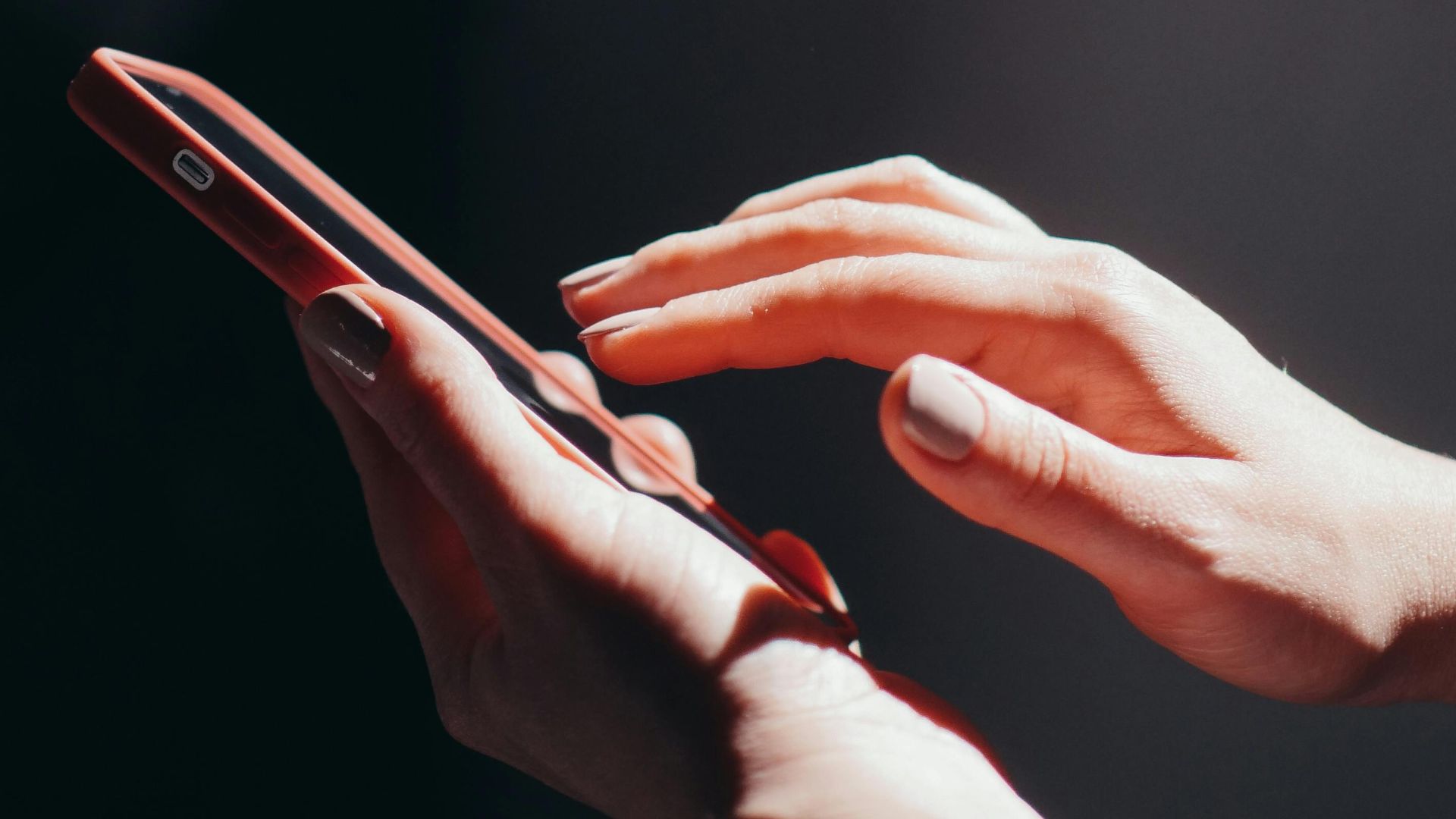 Hands interacting with a smartphone in a well-lit setting, emphasizing connection and technology.