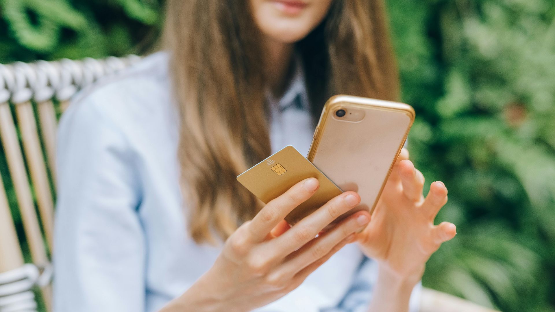 A woman making an online purchase using a smartphone and credit card outdoors.