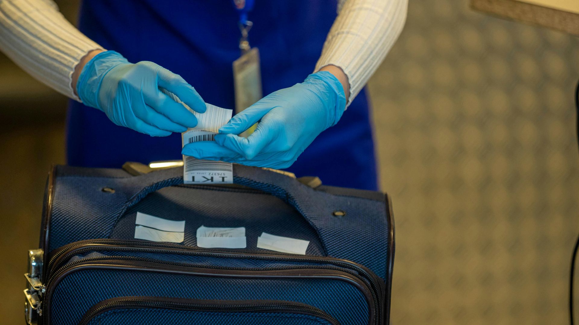 Close-up of airport security process with gloved hands inspecting luggage tags.